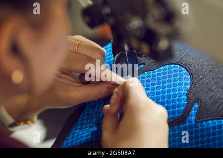 Calzaturificio operaio che utilizza macchina da cucire industriale per rendere dettagli di nuove sneakers Foto Stock