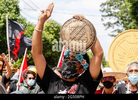 Bangkok, Thailandia. 24 Giugno 2021. Un manifestante a favore della democrazia che fa il saluto a tre dita ha una targa che dichiara "questo paese appartiene al popolo" durante la protesta. Centinaia di dimostranti favorevoli alla democrazia si sono riuniti oggi mattina al Monumento della democrazia a Bangkok per celebrare l'89° anniversario della rivoluzione del 24 giugno 1932 e hanno marciato verso il parlamento per sottolineare la loro domanda in tre punti; Le dimissioni di tutti i 250 senatori nominati dai militari, le dimissioni del primo ministro Prayut Chan-o-cha e la riscrittura della costituzione. Credit: SOPA Images Limited/Alamy Live News Foto Stock