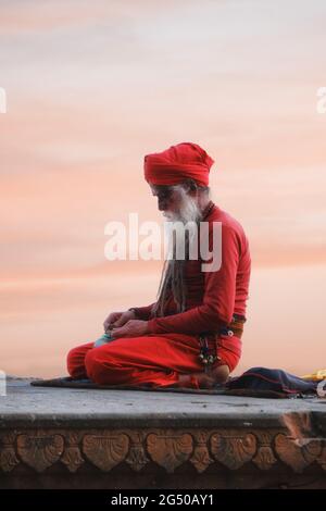 Uomo santo indù sadhu non identificato, siede sul ghat vicino al fiume Gange a Varanasi, India. Foto Stock