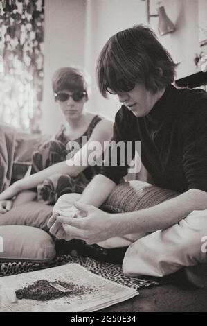 Foto d'epoca di hippies in appartamento arrotolando sigarette con marijuana. STATI UNITI. Marzo 1969 Foto Stock
