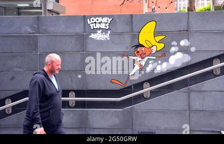 Un uomo accanto a un'immagine di Speedy Gonzales, un personaggio del mouse cartoon, parte di un percorso artistico Looney Tunes che ha aperto a Manchester, Inghilterra, Regno Unito. Il percorso segnerà il film Space Jam: A New Legacy che sarà presto nei cinema a Manchester. Le immagini dei cartoni animati appaiono in 12 località a Manchester. Foto Stock