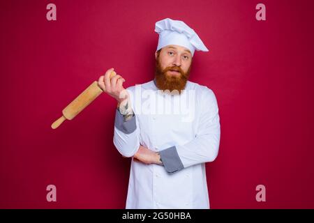 chef pensivo con barba e grembiule rosso con spilla in legno Foto Stock