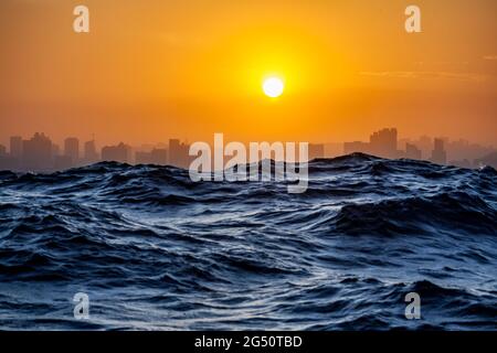 Ci si avvicina a Durban dal mare al tramonto con grandi onde sull'Oceano Indiano, in Sud Africa Foto Stock