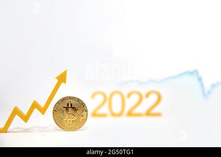 Bitcoin. Prezzo Bitcoin nel 2022. Tasso di criptovaluta popolare. La moneta di Bitcoin sulla tabella dei prezzi punta verso l'alto su uno sfondo bianco Foto Stock