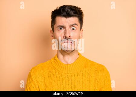 Ritratto fotografico di uomo grimacante disgustato in pullover lavorato a maglia isolato su sfondo di colore beige pastello Foto Stock