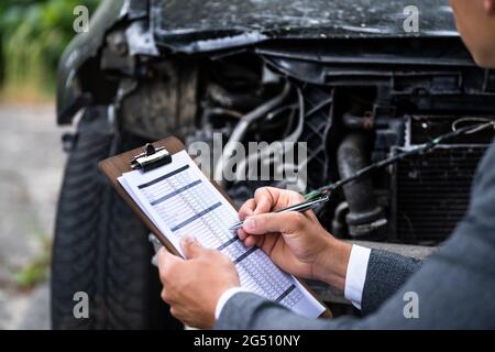 Agente di assicurazione che esamina l'automobile dopo l'incidente o l'arresto anomalo Foto Stock