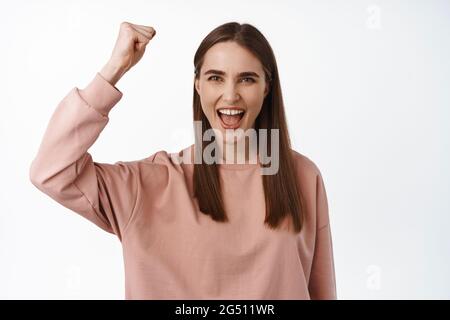 Giovane donna che canta, radica per la squadra. Attivista ragazza che alza la sua prima lotta contro l'uguaglianza, pompa pugno, sembra incoraggiata e determinata, in piedi contro Foto Stock