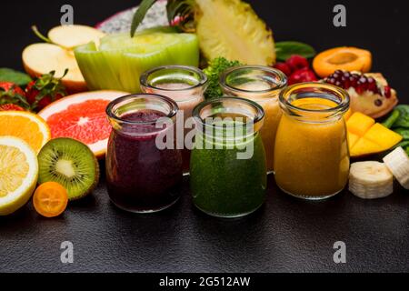 Gruppo di diversi frullati di frutta in bicchieri, verdure e frutta varie Foto Stock