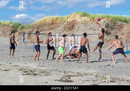 Ragazzi che giocano a Beach volley in una soleggiata giornata estiva a West Wittering, vicino a Chichester, West Sussex, Inghilterra Foto Stock