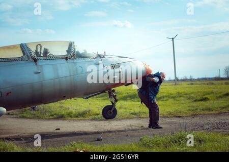 Un uomo di mezza età vicino a un vecchio piano sovietico abbandonato. Aereo sul campo del vecchio aeroporto. Foto Stock