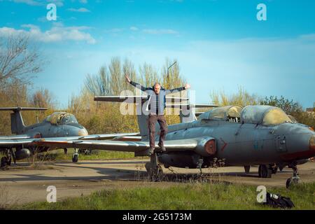 Un uomo di mezza età vicino a un vecchio piano sovietico abbandonato. Aereo sul campo del vecchio aeroporto. Foto Stock