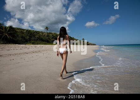 Una giovane donna che cammina sulla spiaggia di Flamenco, nell'isola di Culebra. Porto Rico. Foto Stock