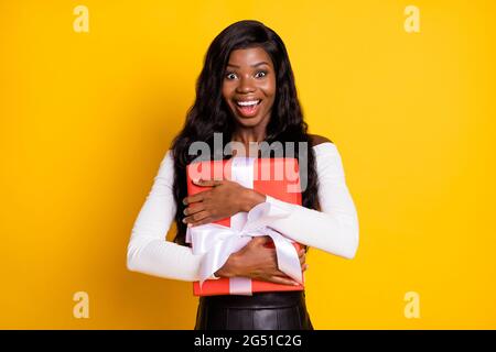 Ritratto fotografico di donna allegra sorpresa tenendo avvolto presente nastro su birhtday sorridendo isolato vivace sfondo giallo Foto Stock