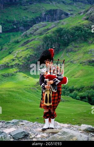 Uomo di abbigliamento tradizionale che gioca a bagpipe, Highlands scozzesi, Scozia, Regno Unito Foto Stock