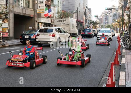 I turisti che guidano vanno i kart mentre indossano i costumi a Tokyo, Giappone Foto Stock