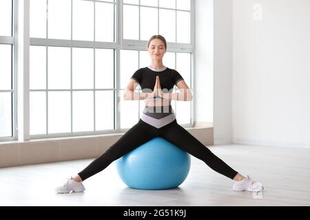 Giovane donna sportiva con flipper che fa yoga in palestra Foto Stock