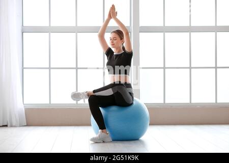 Giovane donna sportiva con flipper che fa yoga in palestra Foto Stock