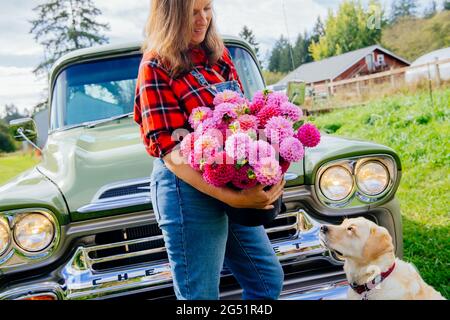 Donna con fiori Dahlia e cane di fronte al camion Foto Stock