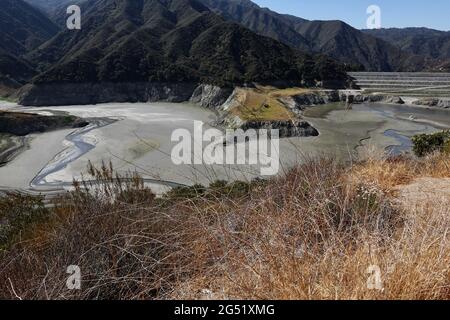 Los Angeles, Stati Uniti. 24 Giugno 2021. Foto scattata il 24 giugno 2021 mostra le coste rocciose e il letto del lago di polvere esposto al lago artificiale di San Gabriel vicino ad Azusa, Los Angeles County, California, Stati Uniti. Anche quest'anno la California deve affrontare una grave siccità. In risposta alle condizioni secche che colpiscono gran parte dello stato, il governatore della California Gavin Newsom ha dichiarato un'emergenza di siccità in due contee della California settentrionale in aprile e ha notevolmente ampliato la proclamazione di emergenza a 41 delle 58 contee dello stato in maggio. Credit: Xinhua/Alamy Live News Foto Stock