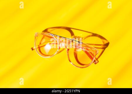 Occhiali da sole rosa alla moda su sfondo giallo. Concetto di accessori estivi - immagine Foto Stock