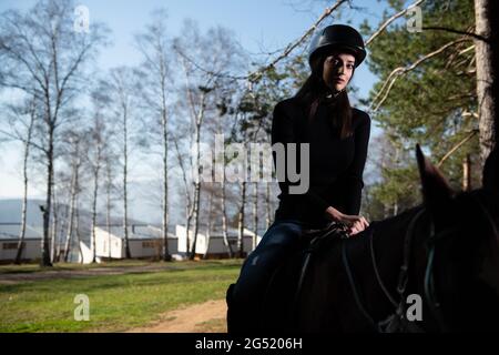 Ritratto di Femminile Jockey sicuro con Cavallo in piedi sul campo Foto Stock