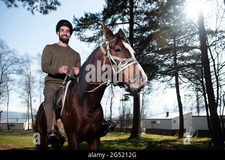 Ritratto di sicuro Jockey maschio con Cavallo in piedi sul campo Foto Stock