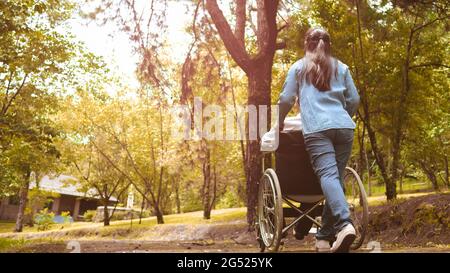 Nonno in sedia a rotelle con nipote che gode della natura nel parco. Vita familiare in vacanza. Foto Stock