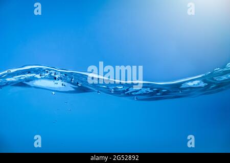 Onde d'acqua con bolle d'aria in acqua blu limpida. Foto Stock