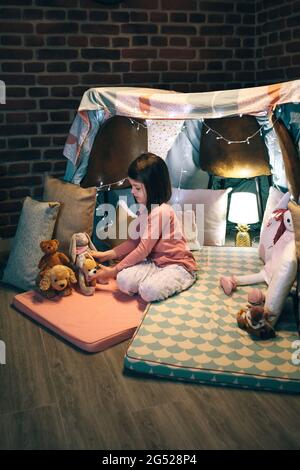 Ragazza che gioca con animali imbalsamati in una teepee Foto Stock