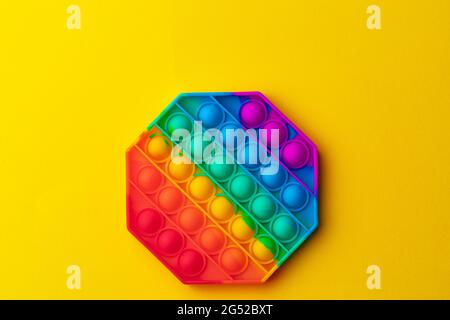 Colorato antistress pop it giocattolo su sfondo giallo Foto Stock