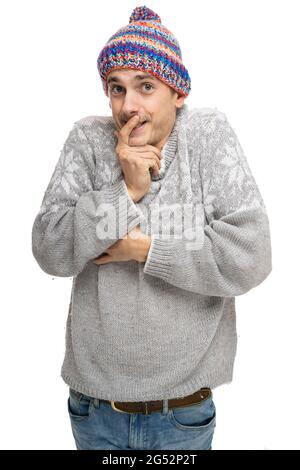 Giovane bell'uomo bianco sottile e alto con i capelli marroni sembra colpevole in ponticello grigio con colorato cappello invernale isolato su sfondo bianco Foto Stock