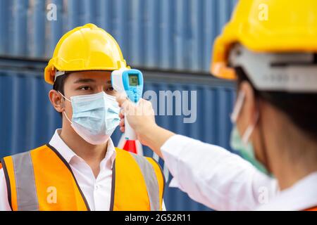 uomo asiatico che indossa maschera viso controllare la febbre da termometro digitale prima di entrare nel lavoro per la protezione da covid, covid-19 o coronavirus p Foto Stock