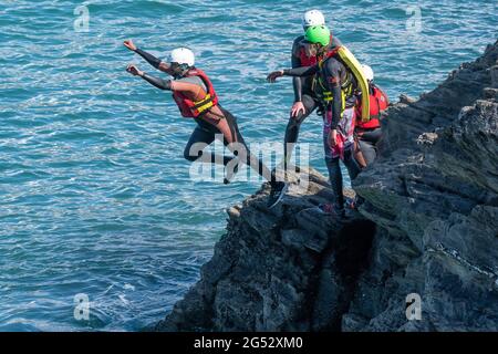 I vacanzieri saltano dalle rocce costellando con una guida su Towan Head a Newquay in Cornovaglia. Foto Stock