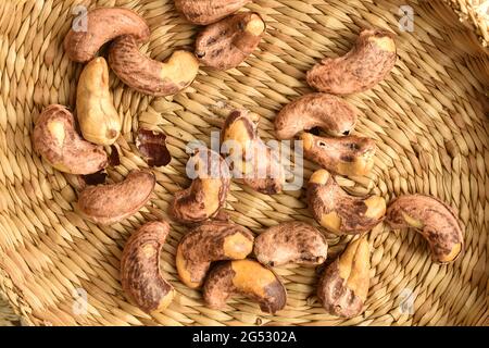 Cashews salati fritti profumati in un piatto di paglia, primo piano, vista dall'alto. Foto Stock