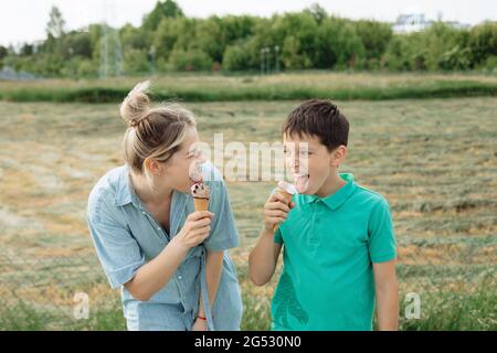 la giovane donna ride insieme con il figlio. Mangiare gelato il giorno d'estate, verde. Momenti felici Foto Stock