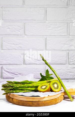 Frutta fresca Verde e verdure: kiwi, menta e asparagi su tavola di legno su sfondo bianco. Ingridiente sano per Smoothie. Cibo vegetariano Foto Stock