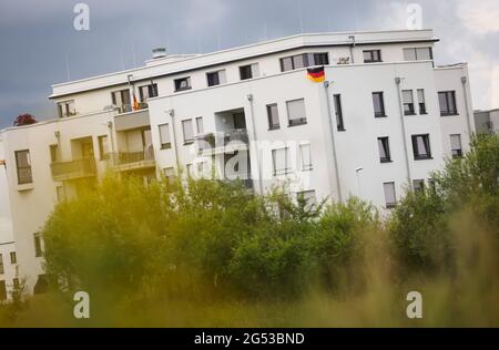 Herzogenaurach, Germania. 25 Giugno 2021. Calcio: Campionato europeo, nazionale, campo di allenamento Germania. Una bandiera tedesca è appesa su un edificio residenziale vicino al sito di Adidas. Per tutta la durata del Campionato europeo, la squadra nazionale tedesca di calcio e il suo personale di supporto vivranno e formeranno presso la sede del partner del DFB Adidas presso il "Home Ground". Nel round del 16, il 29 giugno, la Germania suonerà l'Inghilterra al Wembley Stadium di Londra. Credit: Christian Charisius/dpa/Alamy Live News Foto Stock