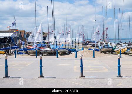 Dinghies vela sulla spiaggia di fronte al Whitstable Yacht Club. La gente fuori e circa godere di una calda giornata estiva al mare. Kent, Inghilterra, Regno Unito Foto Stock