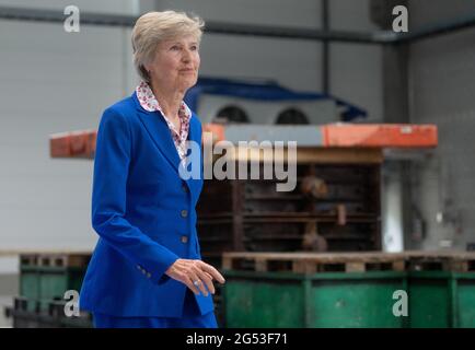 Freiberg, Germania. 25 2021 giugno: Friede Springer, presidente del Consiglio di Amministrazione della Fondazione Friede Springer, passa davanti alla campana (sullo sfondo) alla cerimonia per la fusione di una campana per la Cattedrale di Merseburg a Sächsische Metallwerke a Freiberg. L'occasione per il lancio della campana è il 1000° anniversario della consacrazione della cattedrale di quest'anno. La campana peserà 890 chilogrammi e suonerà in un unico G. il tono si armonizzerà con le altre campane della cattedrale. Il tono si armonizza con le due grandi campane della chiesa. La campana sarà consacrata il 1° ottobre. Credito: Foto Stock