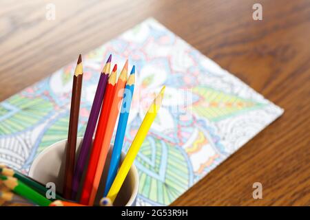 Libro da colorare e pastelli adulti sulla tavola Foto Stock