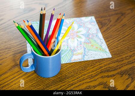 Libro da colorare e pastelli adulti sulla tavola Foto Stock