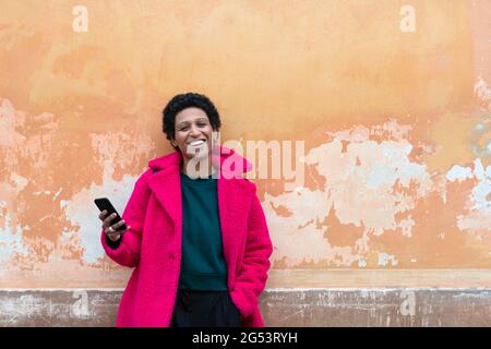 Italia, Toscana, Pistoia, donna sorridente in camice rosa con smartphone Foto Stock