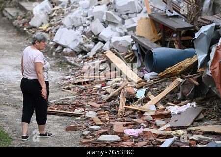 Luzice, Repubblica Ceca. 25 Giugno 2021. Una donna cammina lungo i detriti delle case danneggiate dopo una tempesta di tornado passata attraverso il villaggio Mikulcice nel distretto di Hodonin, Moravia meridionale, Repubblica Ceca, 25 giugno 2021. I villaggi che sono stati colpiti dalla tempesta intensa accompagnata da un tornado il peggiore di tutti sono Moravska Nova Ves, Luzice, Hrusky e Mikulcice. Centinaia di membri della polizia, operatori di soccorso e vigili del fuoco operano nella zona. Le tempeste hanno colpito centinaia di case. Credit: CTK/Alamy Live News Foto Stock