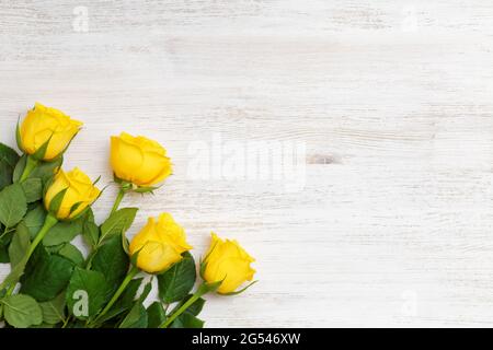 Cinque gemme di rose gialle nell'angolo in basso a sinistra su sfondo bianco di legno Foto Stock