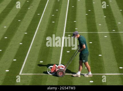 Campo 10 di fronte al Centro Court con i marcatori di prova Hawk-Eye disposti sul campo e un membro del personale di terra che contrassegna le linee come sono state allestite presso l'All England Lawn Tennis and Croquet Club. Data immagine: Lunedì 14 giugno 2021. Foto Stock