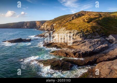 Trebarwith Strand e le scogliere all'estremità nord di Hole Beach lungo la costa rocciosa della Cornovaglia nord. Foto Stock