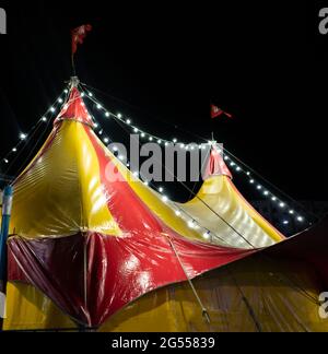 la colorata tenda circense in città di notte contro il cielo Foto Stock