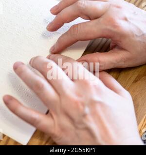 donna leggere libro con braille da dita closeup su tavola legnosa Foto Stock