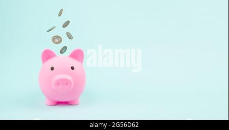 Pink Piggy Bank con monete in caduta, concetto di risparmio. Risparmio finanziario ed economia bancaria. Foto Stock