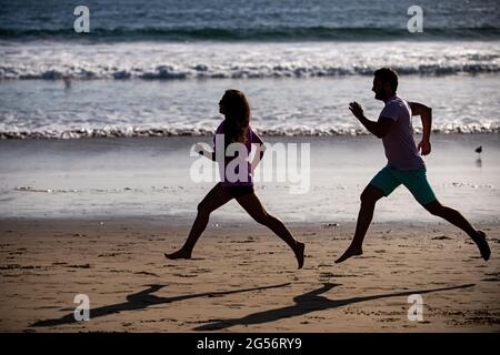 Giovane uomo e donna che corrono a jogging lungo il mare. Coppia che corre sulla spiaggia. Foto Stock